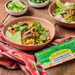 A bowl of El Guapo Chile Serrano Molido Ground Serrano Chili with rice, lime wedges, and jalapenos.