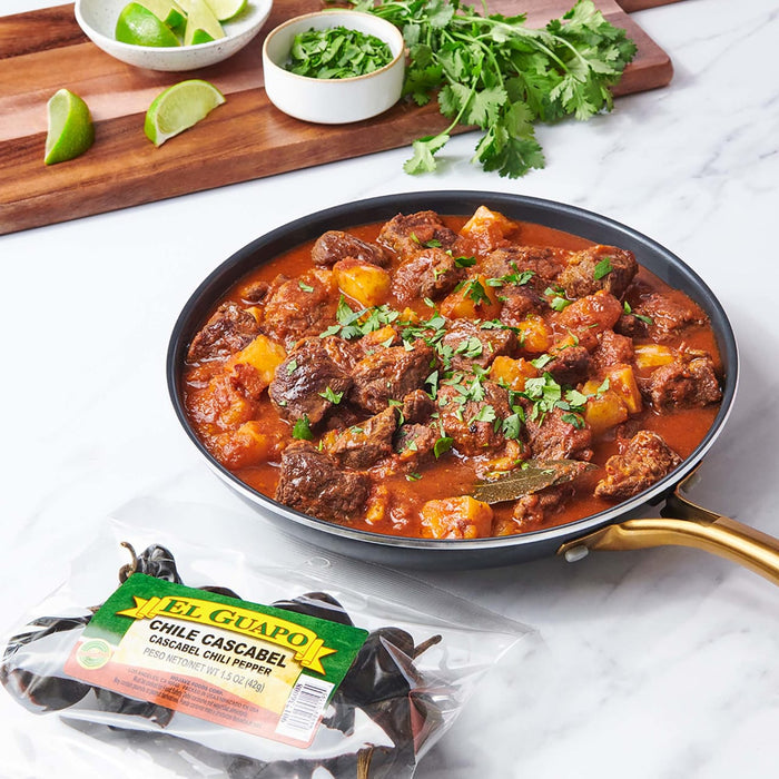 A bag of El Guapo Chile Cascabel chili peppers next to a pan of beef stew.