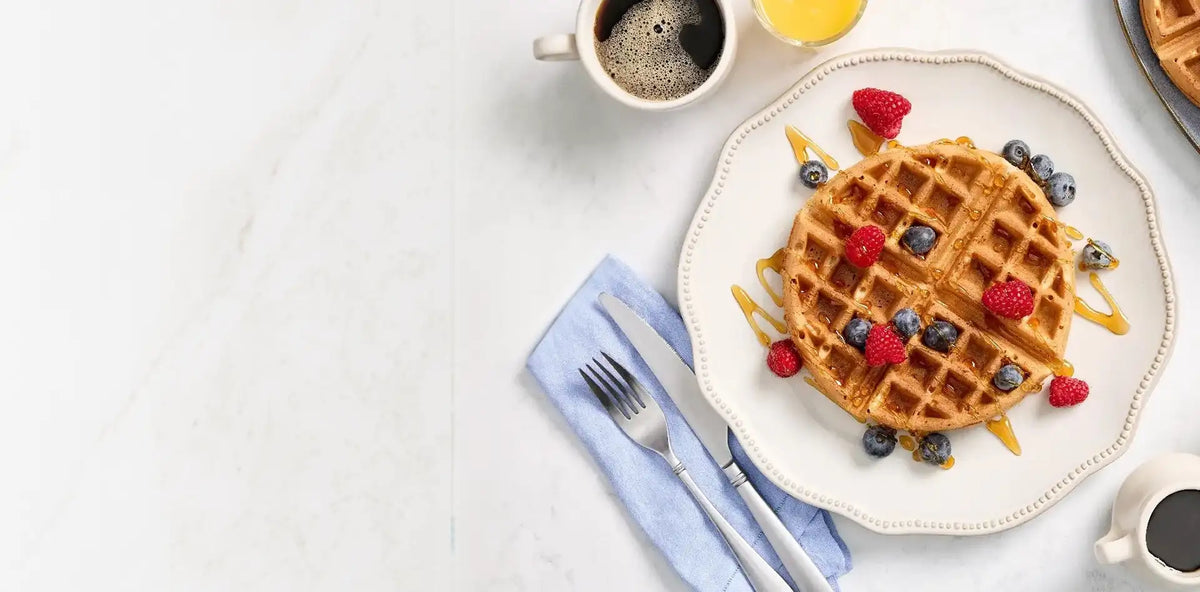 Waffle with berries on a plate with coffee and lemon on a white table