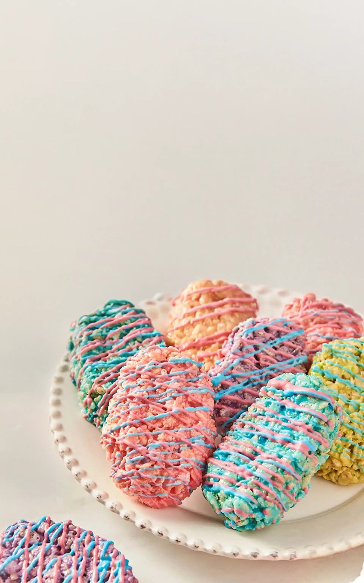 Colorful rice crispy treats on a white plate with a light background