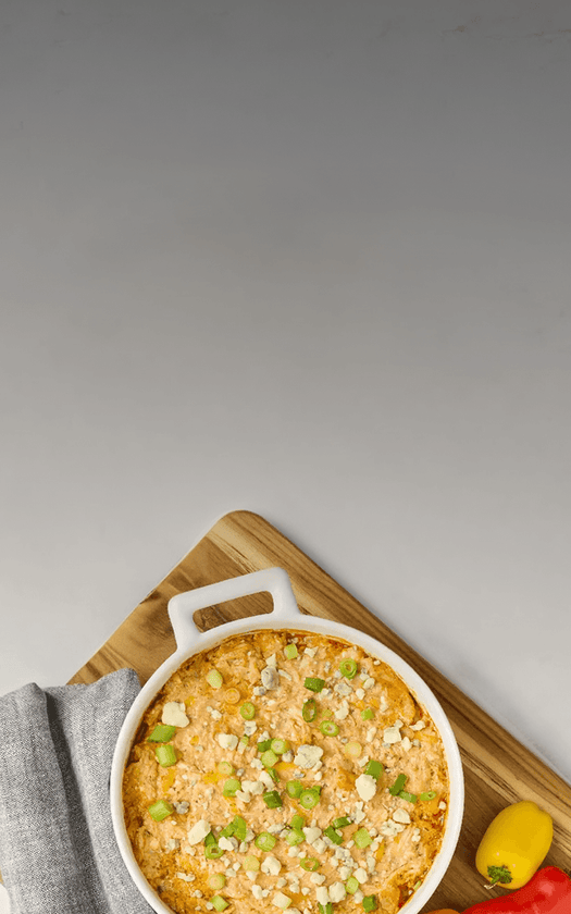 Baked dish with green onions in a white casserole dish on a wooden board.