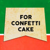 A vintage-style sign with the words For Confetti Cake in black text on a yellow background.