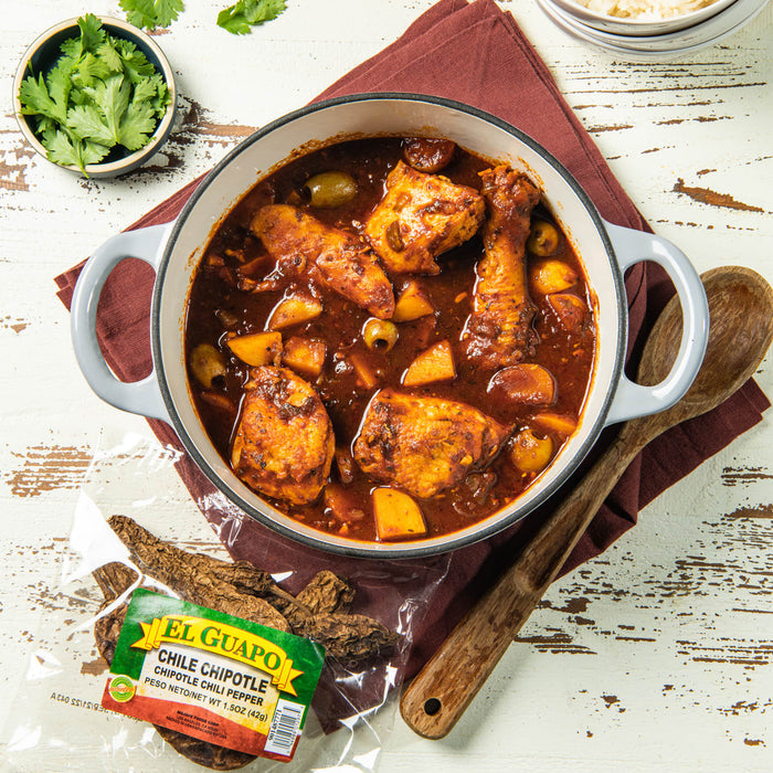 A pot of El Guapo Chile Chipotle Chili Pepper with a wooden spoon and a bag of dried peppers.