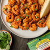 A plate of El Guapo seasoned annatto paste shrimp with cilantro and toasted bread.