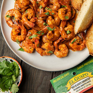 A plate of El Guapo seasoned annatto paste shrimp with cilantro and toasted bread.