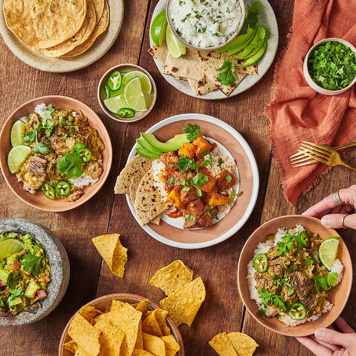 A table with a variety of Mexican dishes, including rice, beans, and tortillas.