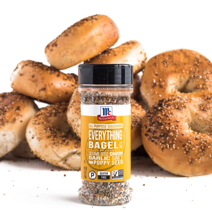 A jar of McCormick Everything Bagel seasoning sits in front of a pile of bagels.