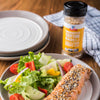 A plate of salmon with everything bagel seasoning, a side salad, and a jar of McCormick Everything Bagel Seasoning.