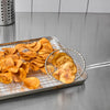 A metal tray with a wire rack holds a pile of homemade potato chips, some of which are being scooped up with a wire skimmer.