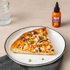 A slice of pizza topped with Frank's RedHot Squeeze Creamy Buffalo Sauce.