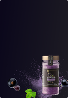Bottle of black currant powder with black currants and a leaf on a dark background