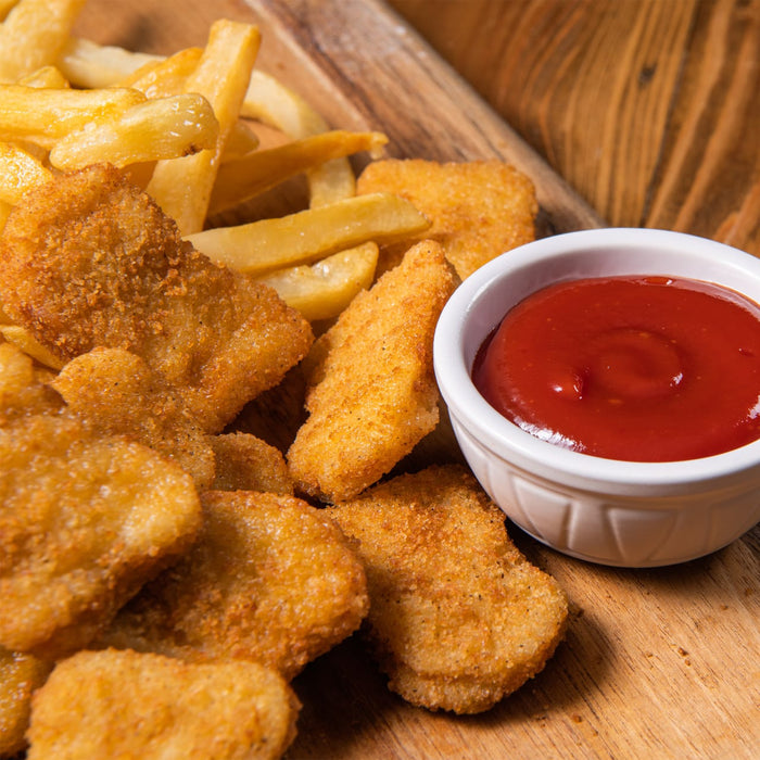 A close-up shot of crispy golden chicken nuggets and french fries on a wooden board, accompanied by a small white bowl of bright red French'S Tomato Ketchup (Case Of 9).