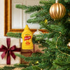 A festive Christmas tree is decorated with a unique ornament shaped like a bottle of Frenchs Classic Yellow Mustard hanging among gold baubles and lights.