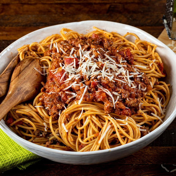 A bowl of spaghetti with meat sauce and parmesan cheese.