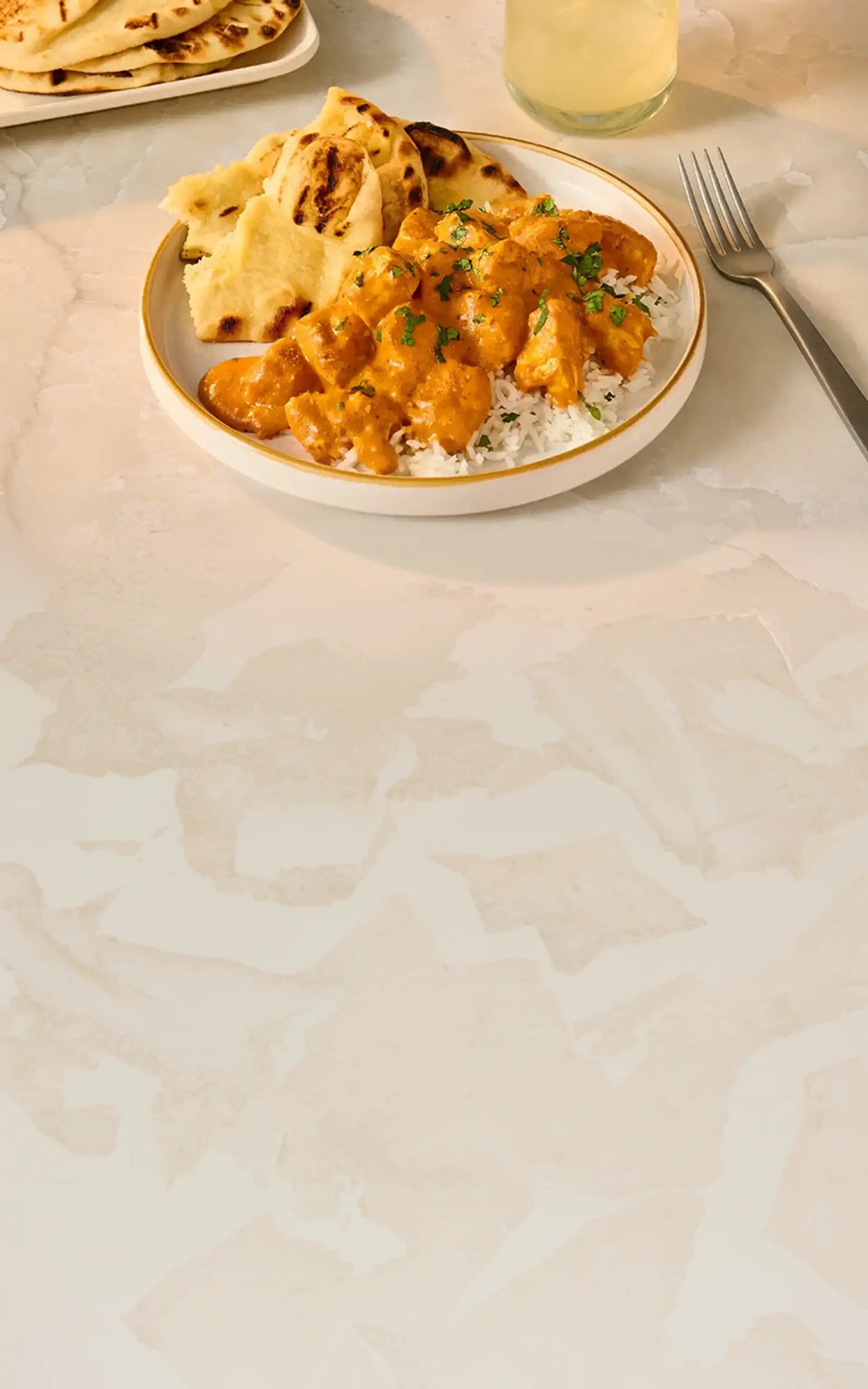 Plate of cauliflower curry with naan bread on a light surface