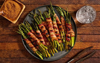 Wrapped asparagus on a dark plate with a wooden background