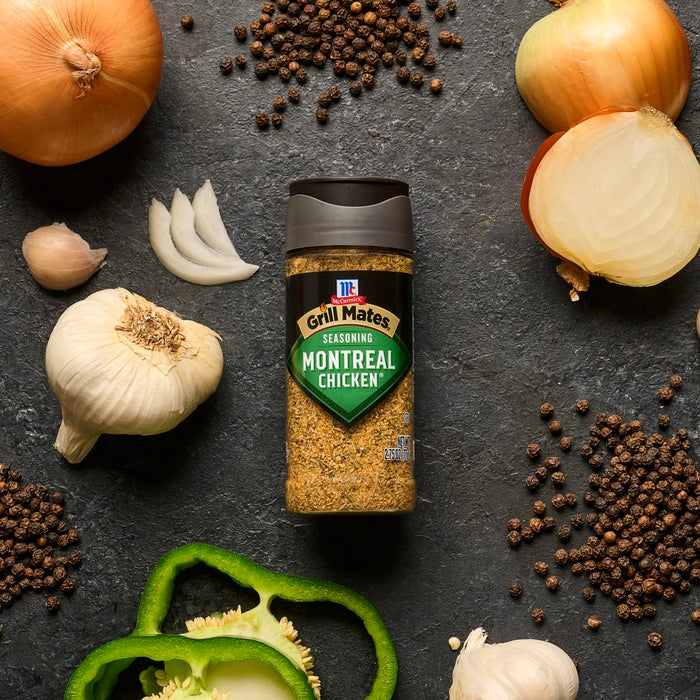 A bottle of McCormick Montreal Steak Spice is surrounded by onions, garlic, peppercorns, and green bell pepper, showcasing its ingredients.