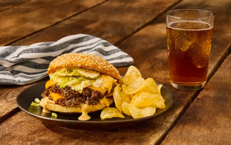 Hamburger with chips and a glass of beer on a wooden table