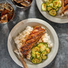 A beautifully plated meal of glazed salmon over rice and a side of seasoned cucumbers demonstrates a delicious recipe idea using Mccormick Grill Mates Hawaiian Style Bbq Meat Marinade Mix 1.25 Oz.
