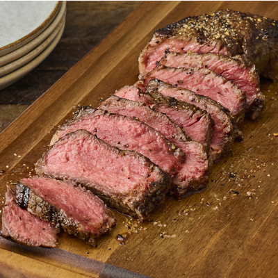 Sliced steak on a wooden cutting board with a knife