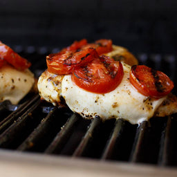 Grilled chicken breast with cherry tomatoes on a grill