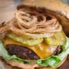 A juicy burger topped with cheese, pickles, onion rings, and lettuce.