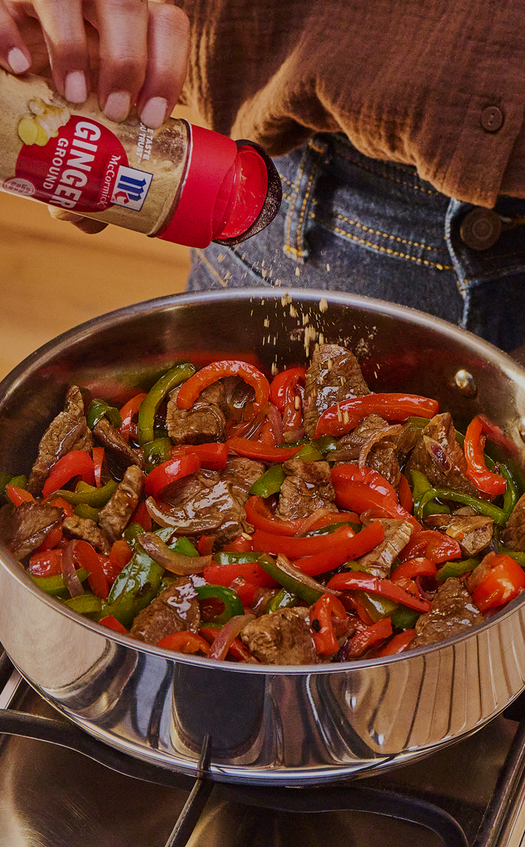 Person seasoning stir-fry with McCormick ginger ale seasoning