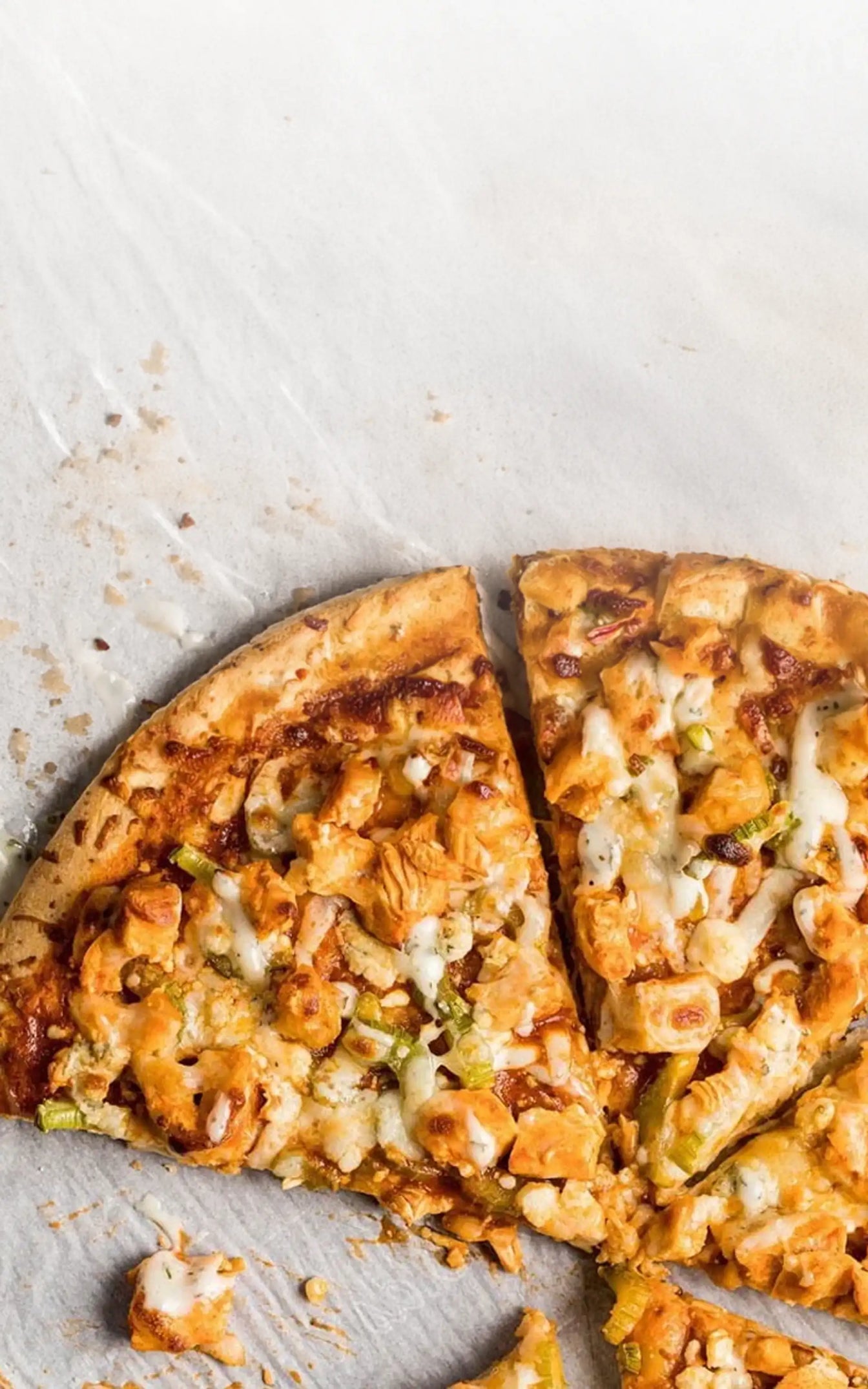 Slice of pizza with chicken and cheese on a white surface