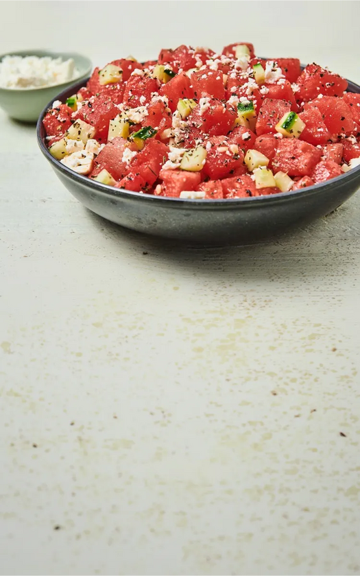 Bowl of watermelon salad with feta cheese on a light surface