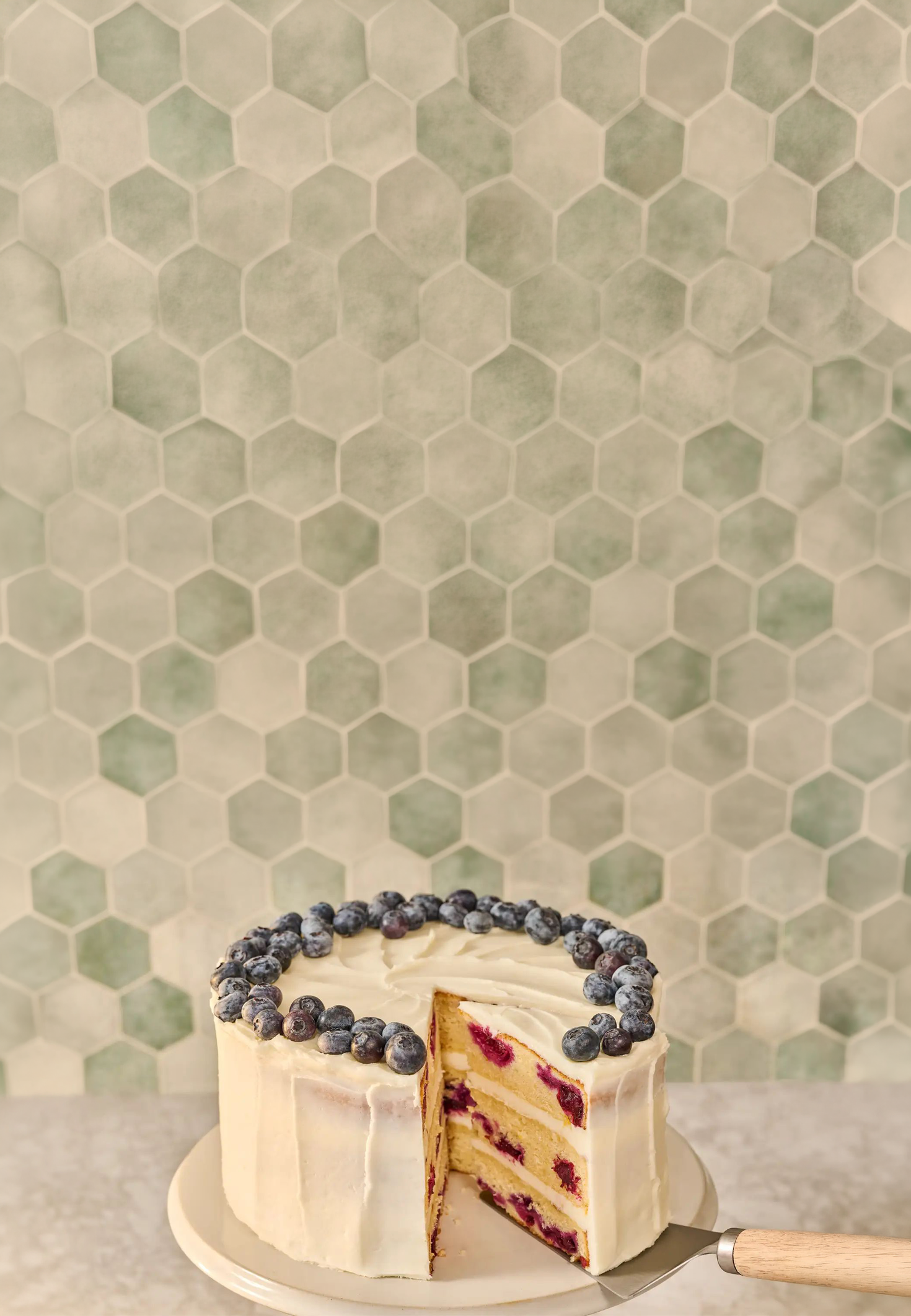 Lemon blueberry cake with a hexagonal-patterned wall in the background
