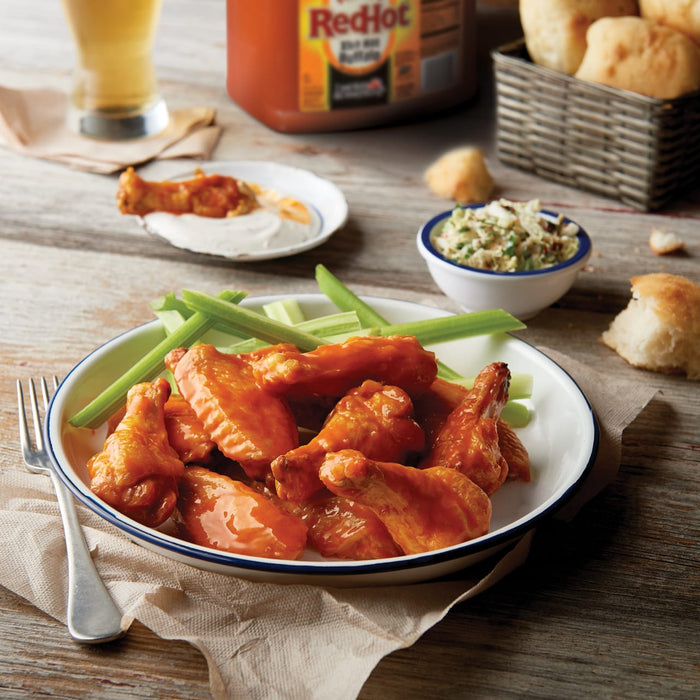 A plate of RedHot Buffalo wings with celery sticks and a fork.