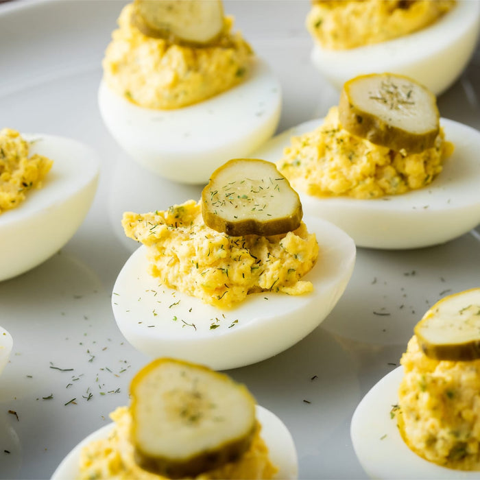 Deviled eggs topped with dill pickle slices and dill.