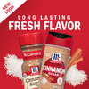 Two containers of McCormick Cinnamon Sugar, one with a red lid and the other with a black lid, are shown on a red background with white sugar crystals and cinnamon sticks.
