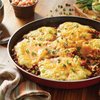 A skillet of cheesy cornbread topped with green onions.