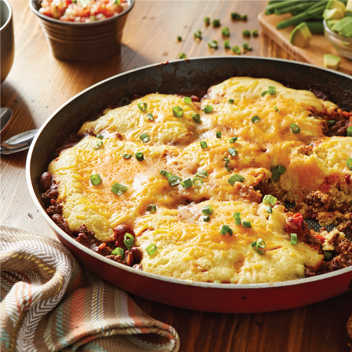 A skillet of cheesy cornbread topped with green onions.