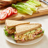 Two chicken salad sandwiches on whole wheat bread with lettuce, tomato, avocado, and celery.