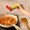 A hand sprinkles McCormick Garlic &amp; Olive Oil seasoning onto shrimp cooking in a pan.