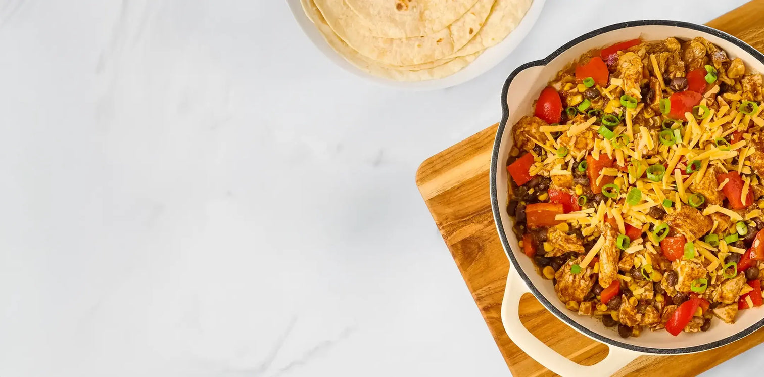 Bowl of Mexican-style rice with vegetables on a wooden cutting board.
