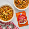 Two bowls of beef stew with pasta are displayed next to a packet of McCormick Slow Cookers Beef Stew seasoning mix.