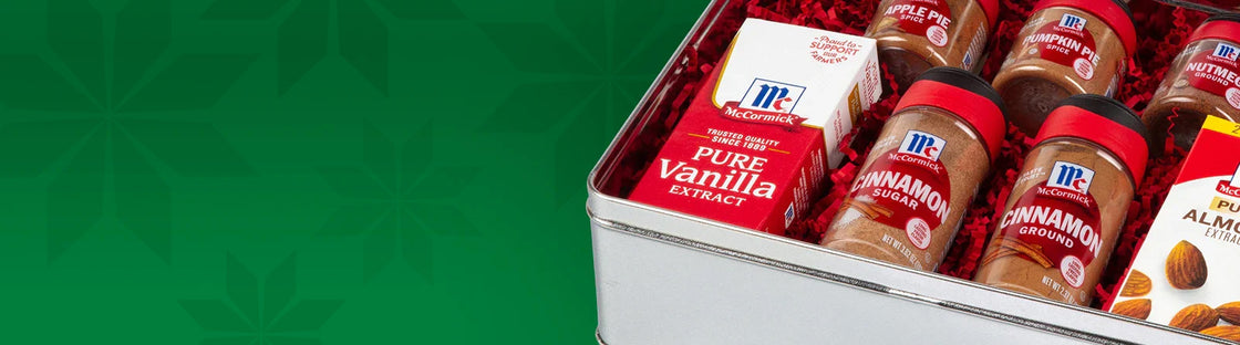 McCormick spice gift set including vanilla extract, cinnamon, pumpkin pie spice, nutmeg, and almond extract in a festive tin.