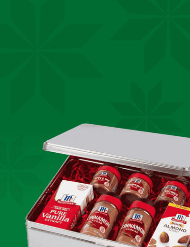 McCormick gift tin with assorted spices and extracts against green background.