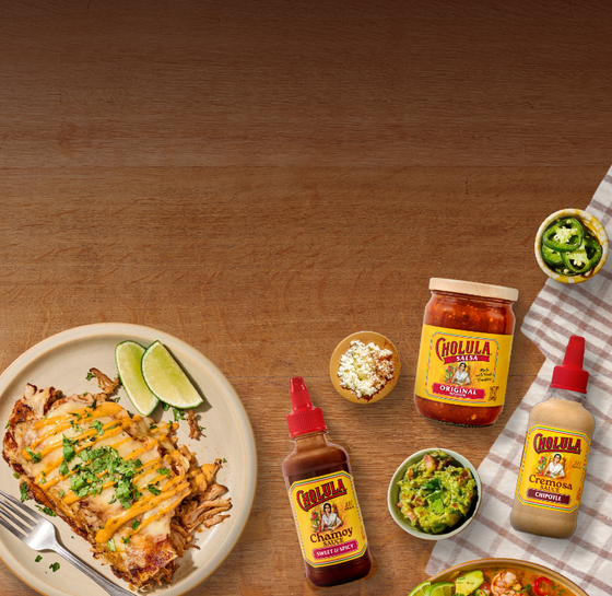 Dishes of food with Cholula sauce bottles on a wooden table