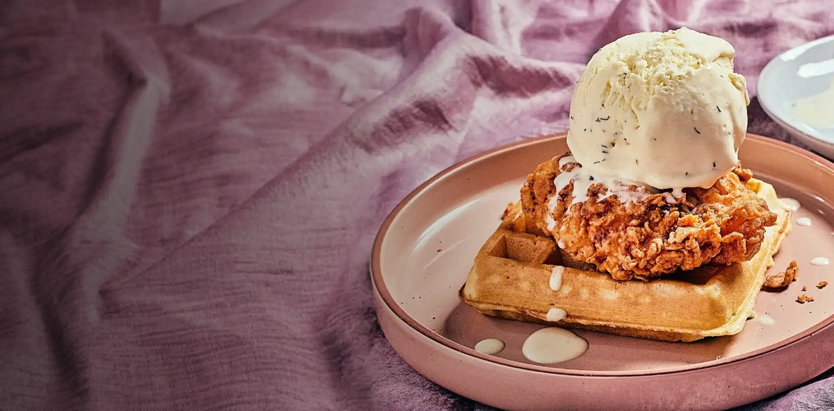 Plate of fried chicken and waffles with ice cream on a pink fabric background