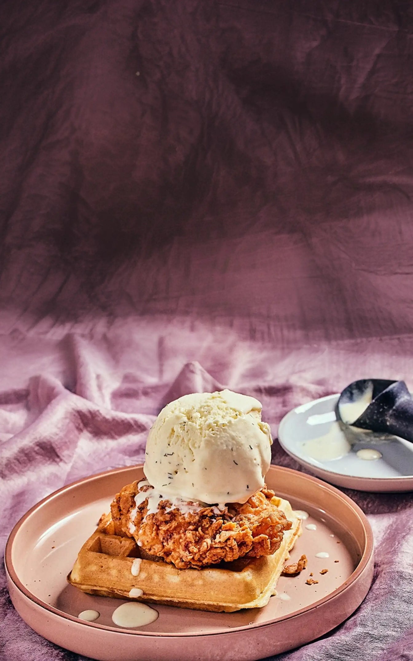 Plate of fried chicken and waffles with ice cream on a pink fabric background