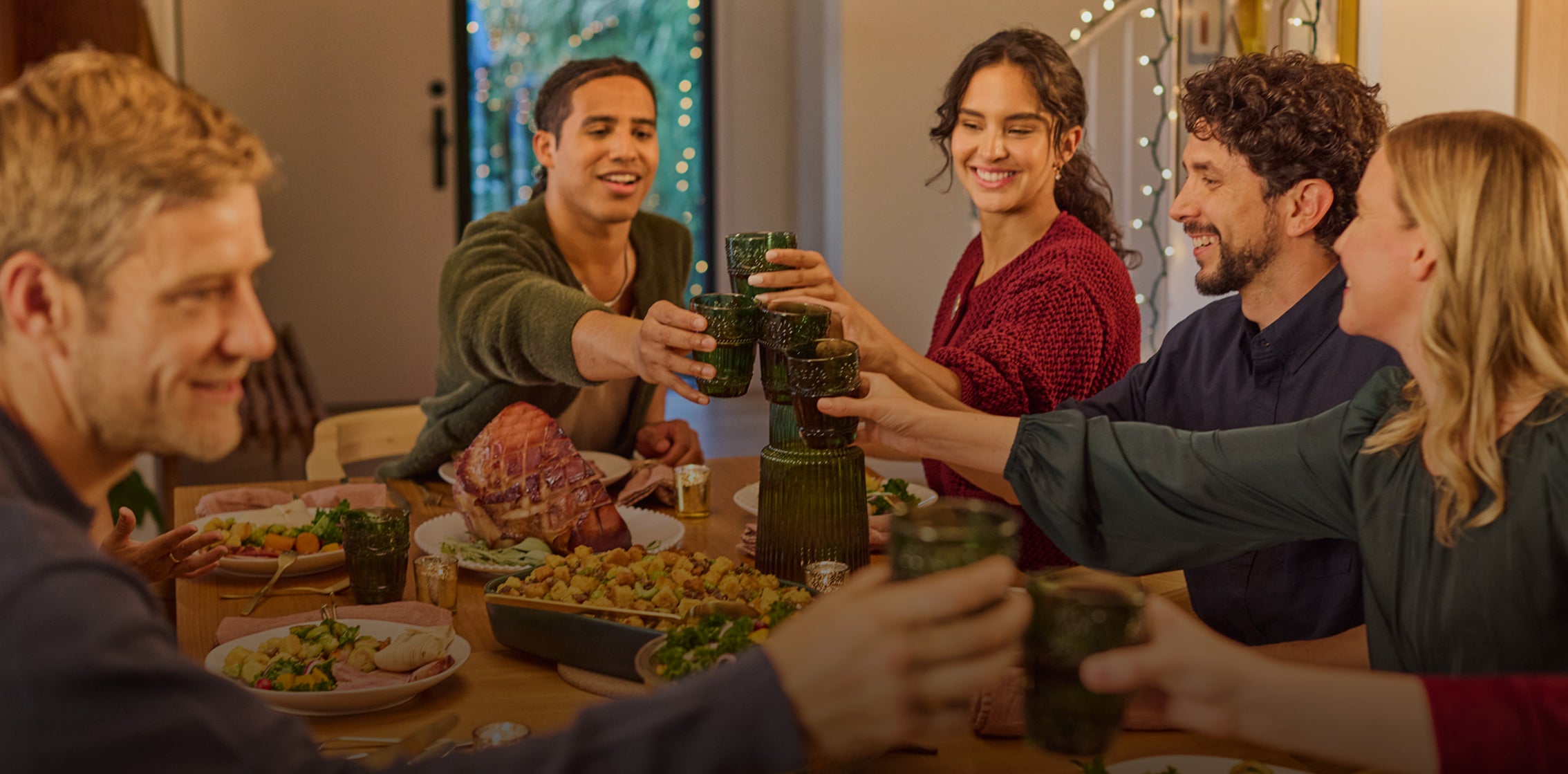 Group of people enjoying a meal together with drinks, smiling and toasting.