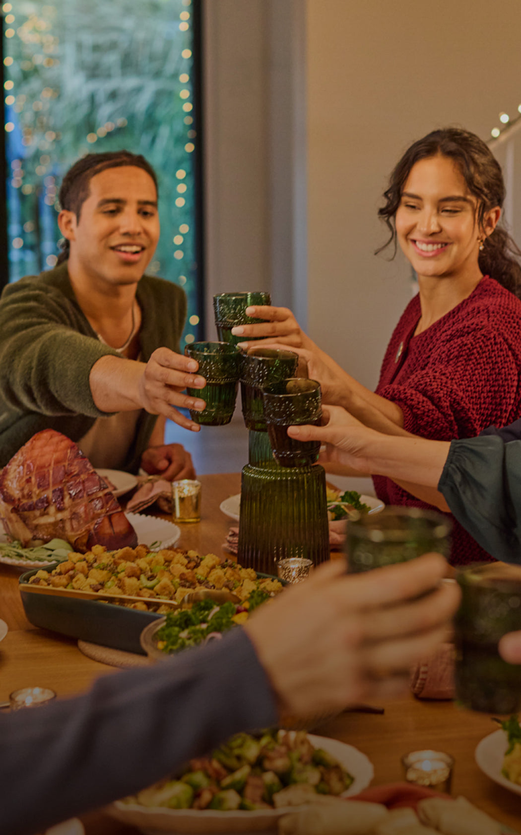 People toasting with glasses at a festive dinner table with a decorated background