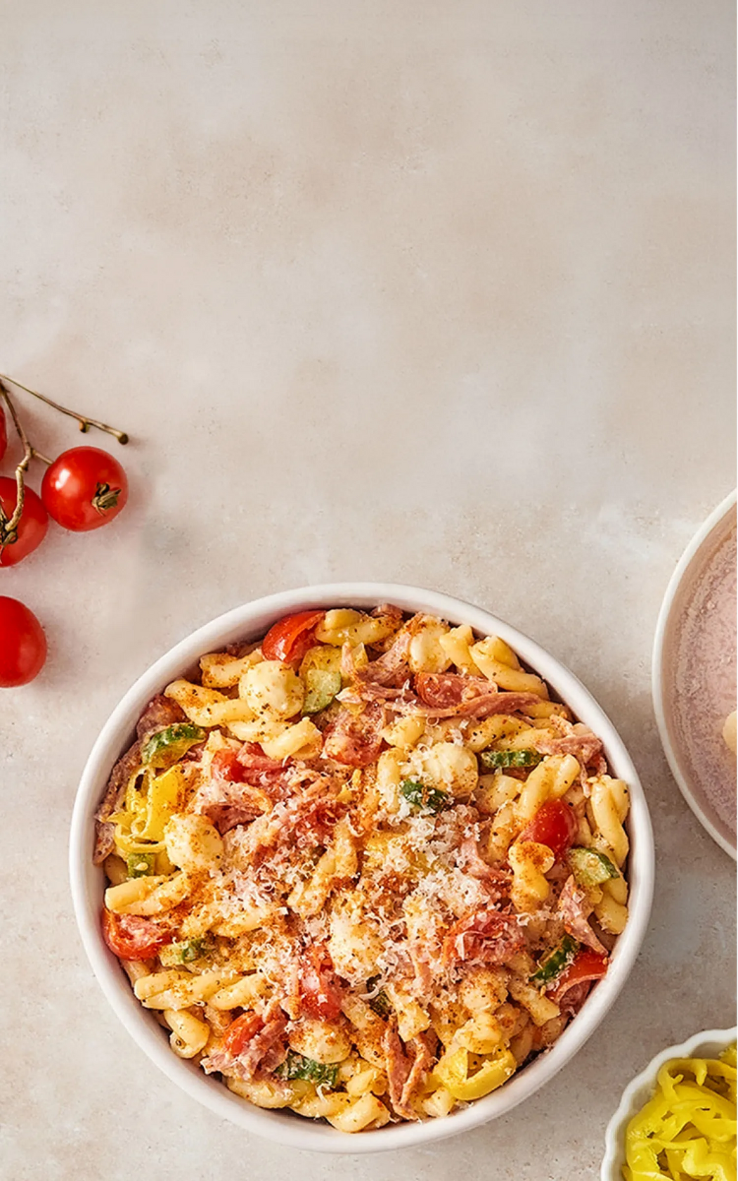 Pasta dish with tomatoes and herbs in a white bowl on a light background