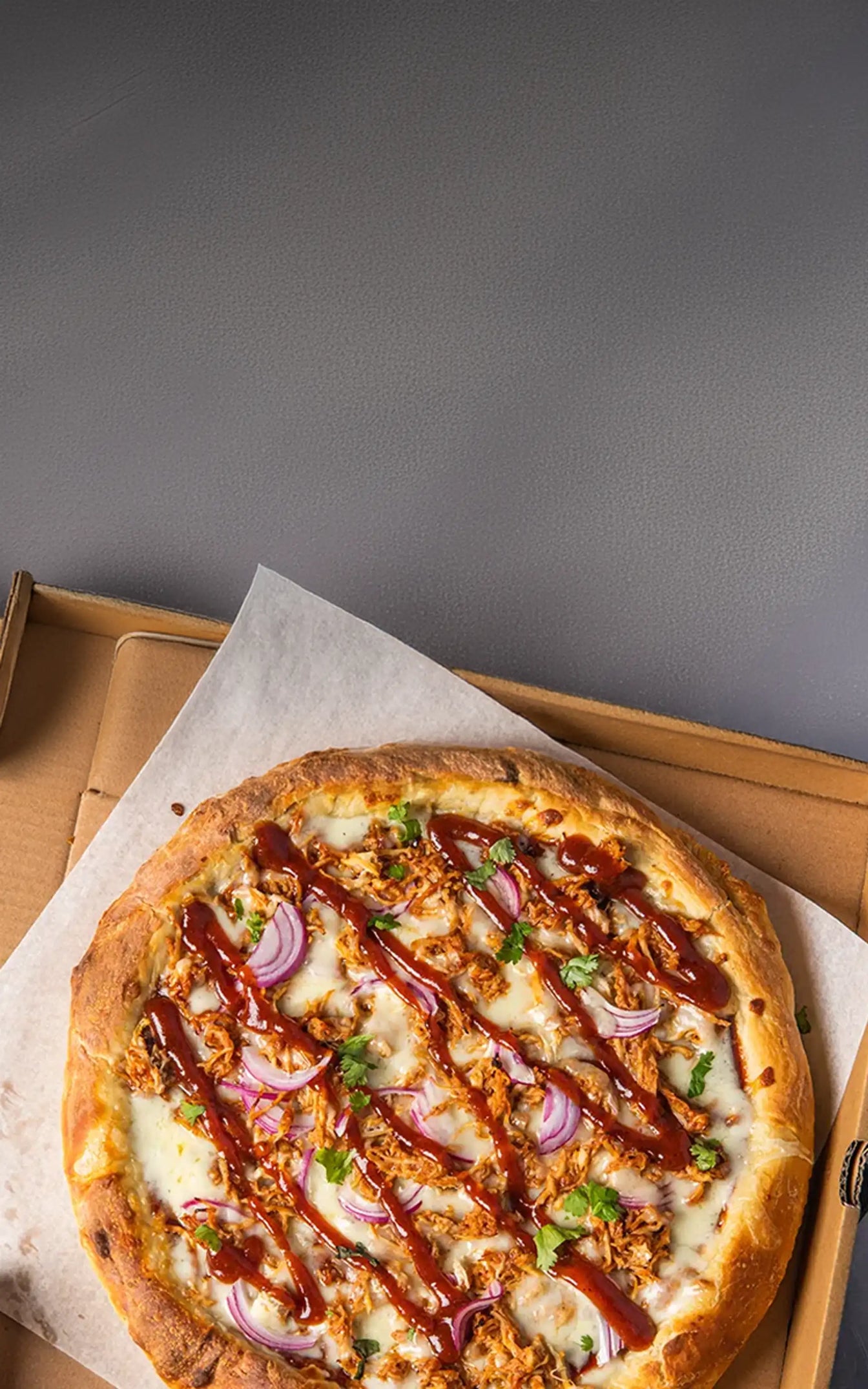 BBQ pizza with onions and green herbs on a cardboard box