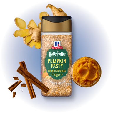A jar of McCormick Harry Potter Pumpkin Pasty Finishing Sugar centered on a white background with a soft blue glow, surrounded by ginger roots, cinnamon sticks, and a small bowl of the pumpkin paste.