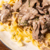 ['A close-up of a plate of creamy beef and noodles.']